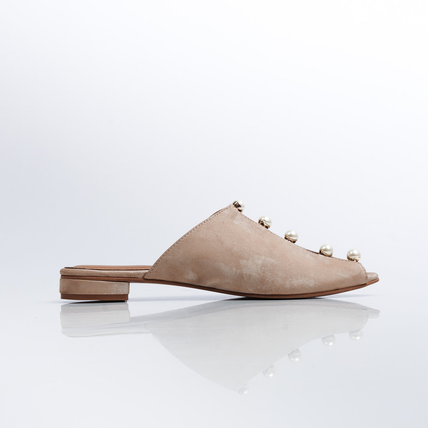 Beige slip-on shoe with decorative elements on a white background
